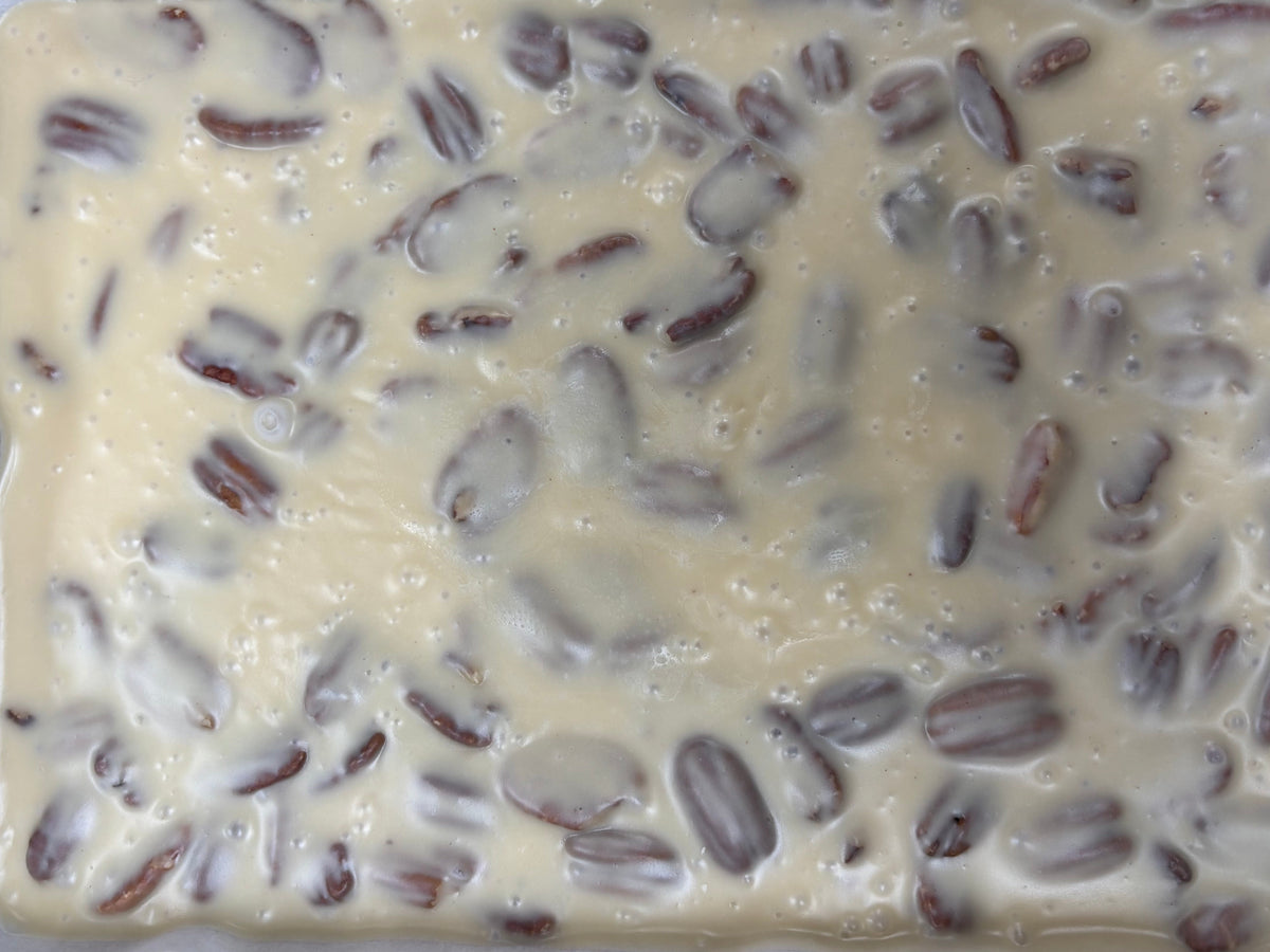 Uncut slab of freshly made Butter Pecan Fudge in parchment paper lined an.